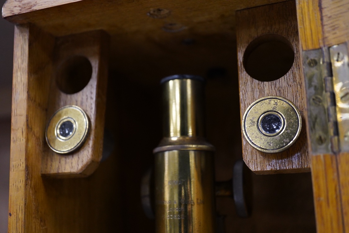 An early 20th century oak cased brass ‘Kima’ microscope by W. Watson & Sons Ltd. London, with engraved serial number under the maker’s name; 53622, with two alternative lenses in fitted compartments, microscope approxima